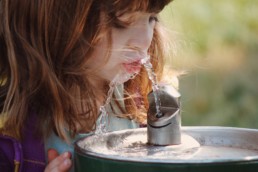 Girl drinking from water fountain.