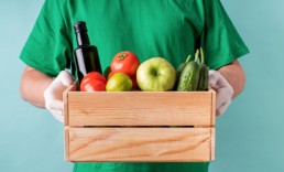 Male hands holding a wooden box of food supplies